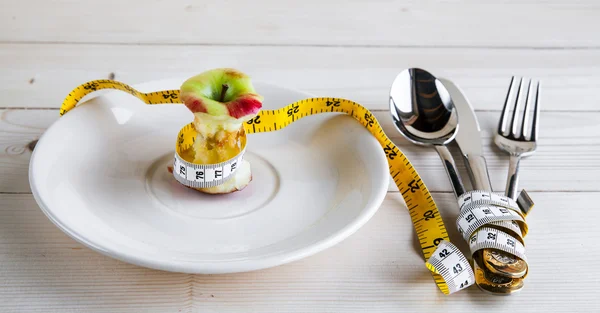 Plate with stub, measure tape, knife and fork. Diet food on wooden table