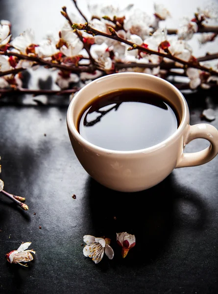 Cup of coffee and pink cherry blossoms. flowers