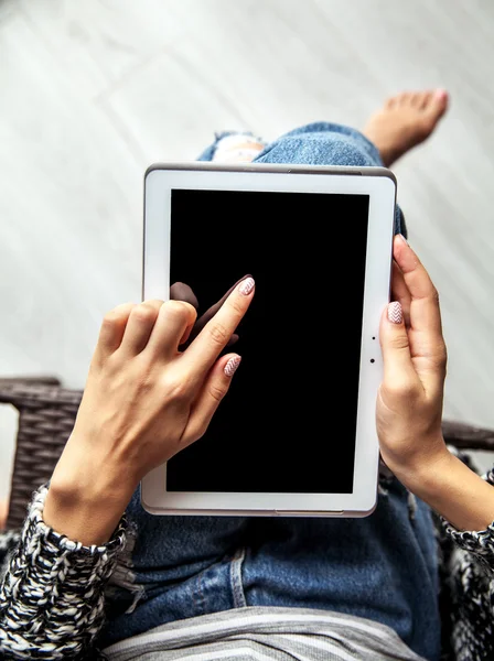 Woman holding and using tablet with empty screen, ripped jeans
