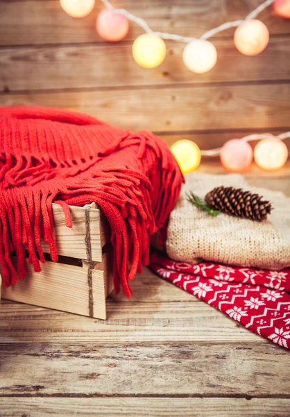Christmas set. Warm blanket, sweater, socks, garland and a bump on the wooden background