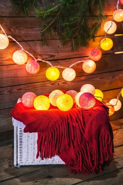 Christmas set. Warm blanket, sweater, socks, garland and a bump on the wooden background