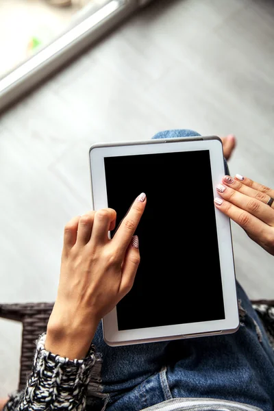 Woman holding and using tablet with empty screen, ripped jeans