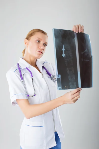 Healthcare and medical concept - female doctor with stethoscope examining an X-ray