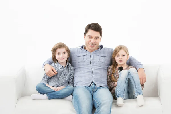 Family sitting on sofa smiling at camera on white background