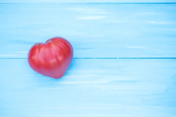 Tomato heart on a blue table.