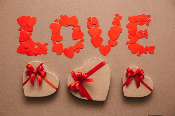 Word Love from hearts and gift boxes in the shape of hearts. Gifts for Valentine\'s Day.