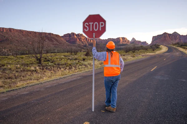 A construction worker stopping traffic, holding a stop sign.