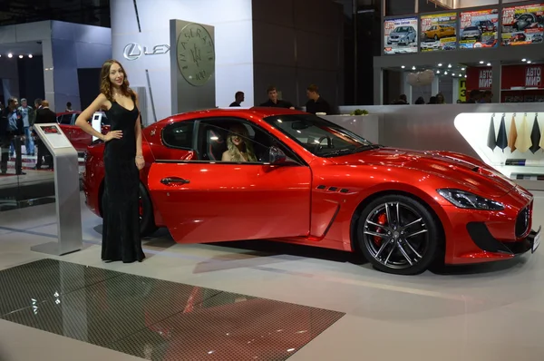 A young woman from the Maserati team. In the long black dress near car. Gran Turismo. Red Car. Moscow International Automobile Salon Shine
