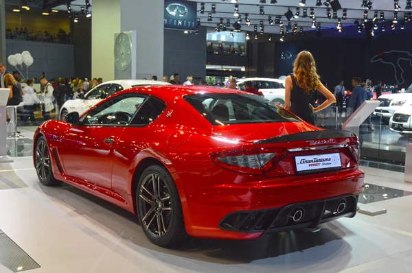 A young woman from the Maserati team. In the long black dress near car. Gran Turismo. Red Car. Moscow International Automobile Salon Traffic