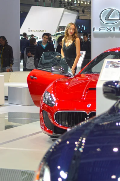A young woman from the team Maserati near car. Moscow International Automobile Salon Red and Dark Blue Maserati