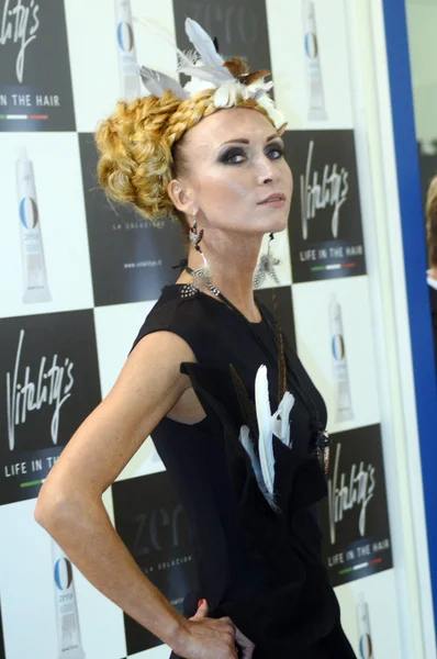 Intercharm XXI International Perfumery and Cosmetics Exhibition Beautiful young blonde woman with stylish hairstyle in black dress from the well-known company for the production of  hair care