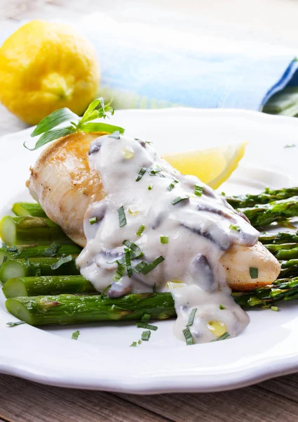 Fried chicken breast on asparagus with tarragon and mushroom sauce