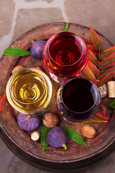 Red, rose and white glasses and bottles of wine with grapes in wine cellar