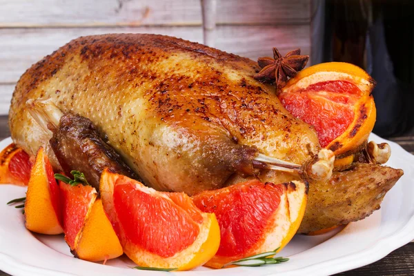 Festive Christmas duck baked with grapefruits and rosemary, glass of wine and candles