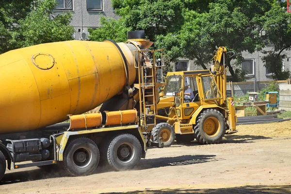 Cement mixer truck and an excavator at the construction site