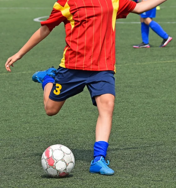 Young soccer player kicks the ball