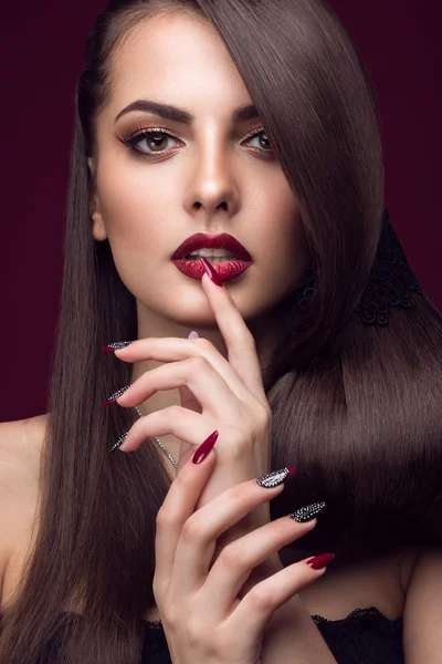 Pretty girl with unusual hairstyle, bright makeup, red lips and manicure design. Beauty face. Art nails.