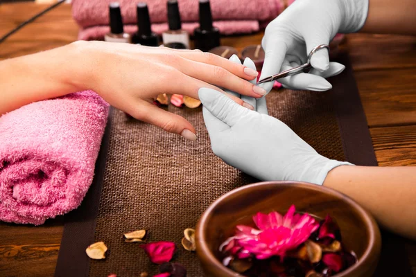 Closeup finger nail care by manicure specialist in beauty salon.