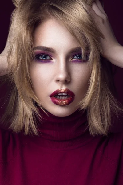 Beautiful blonde woman in a red sweater with bright makeup and dark lips. Beauty face.