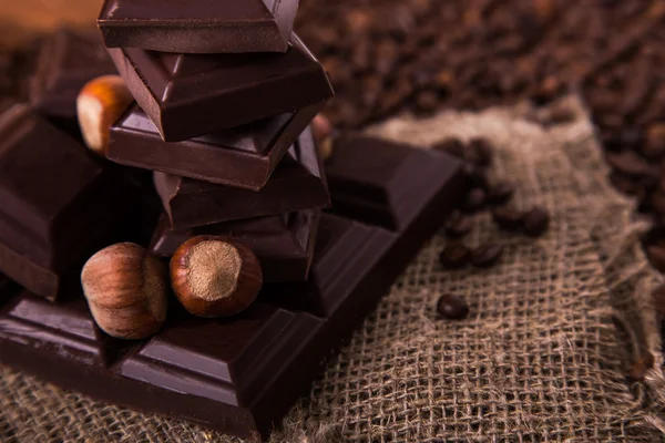 Roasted coffee beans, chocolate and nuts on the wooden background