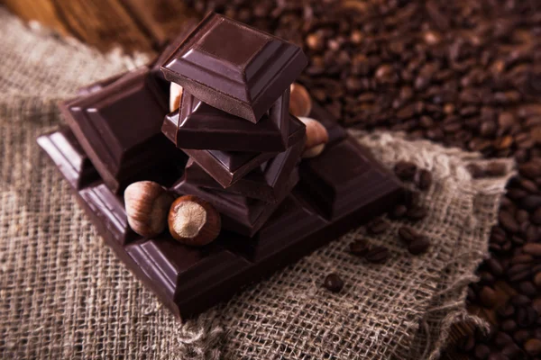 Roasted coffee beans, chocolate and nuts on the wooden background