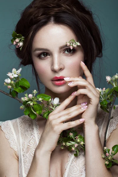 Beautiful brunette girl in lingerie with a gentle romantic make-up, pink lips, holding flowers. The beauty of the face.