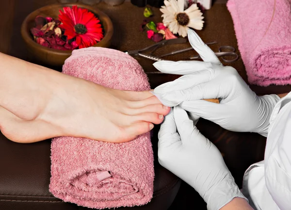 Closeup finger nail care by pedicure specialist in beauty salon.