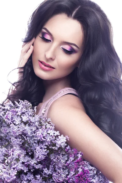 Beautiful brunette girl with a gentle romantic make-up, pink lips and flowers. The beauty of the face.