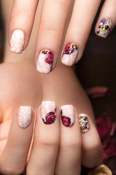 Beautiful manicure with flowers on female fingers. Nails design. Close-up