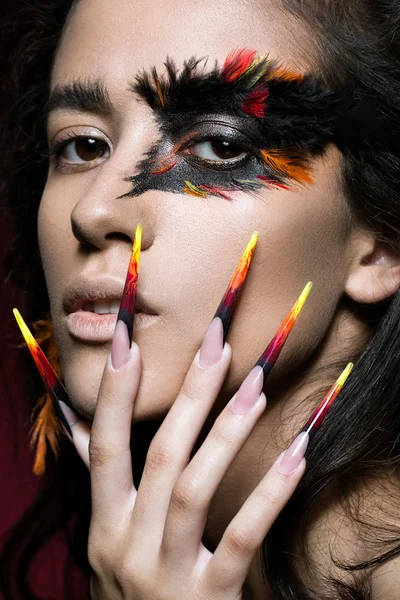 Beautiful girl in image of Phoenix bird with creative makeup and long nails. Manicure design. beauty face.