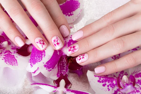 Shot beautiful manicure with flowers on female fingers. Nails design. Close-up