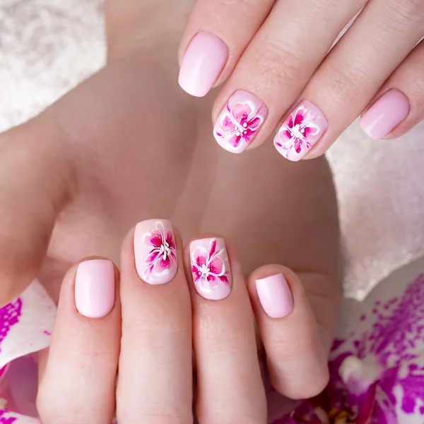 Shot beautiful manicure with flowers on female fingers. Nails design. Close-up