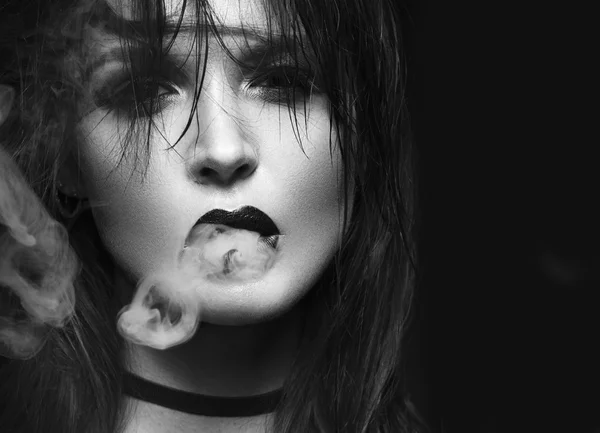 Beautiful sexy brunette girl with bright makeup, red lips, smoke from mouth. beauty face. Black and white