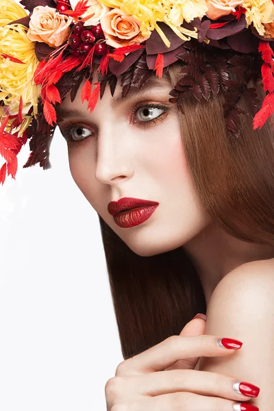 Beautiful red-haired girl with bright autumn wreath of leaves and flowers. Beauty face.