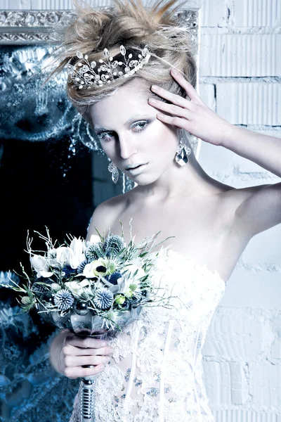 Beautiful girl in white dress in the image of the Snow Queen with a crown on her head.