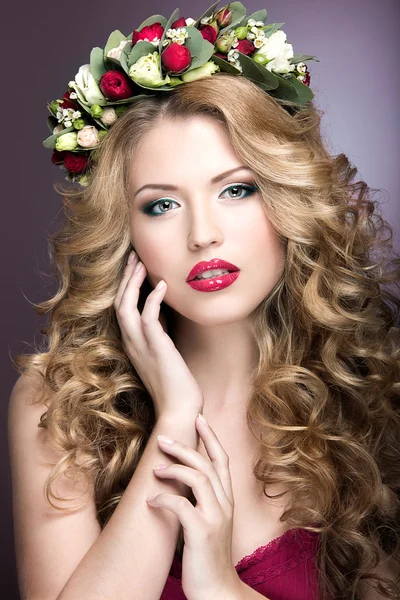 Portrait of a beautiful blond girl with curls and wreath of purple flowers on her head. Beauty face.