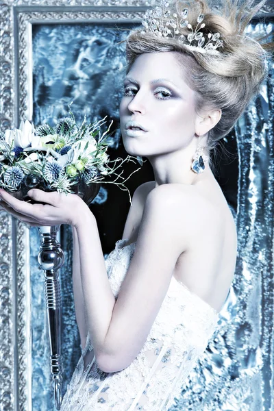 Beautiful girl in white dress in the image of the Snow Queen with a crown on her head.