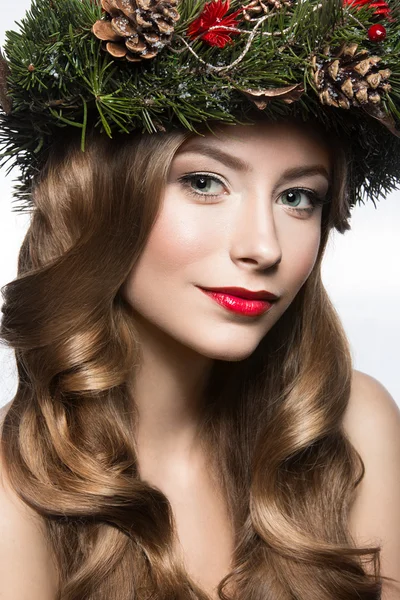 Beautiful girl with a wreath of fir branches and cones. New Year image. Beauty face.