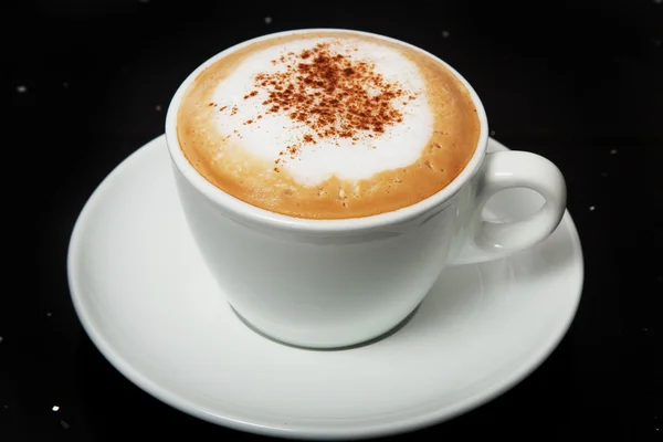 Cappuccino with cinnamon in a white cup.