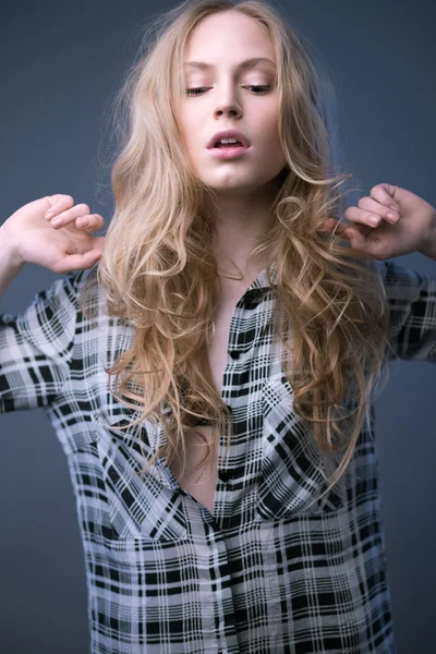 Beautiful blonde girl in a shirt with a light makeup and loose hair. Model tests.