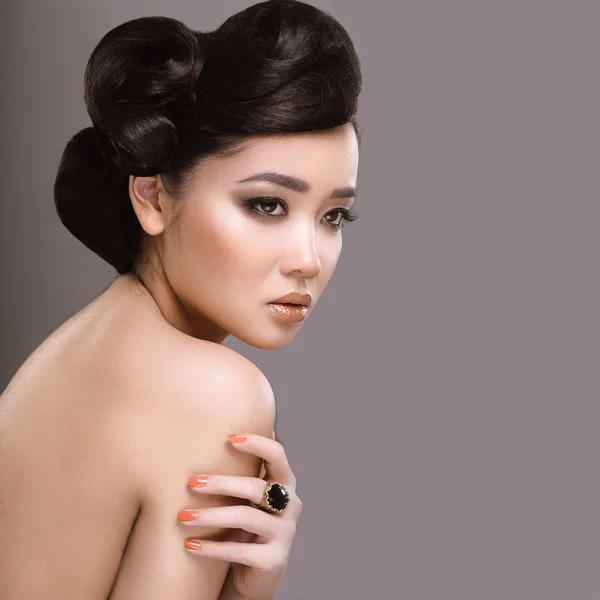 Beautiful girl with oriental type evening hair and makeup. Beauty face.