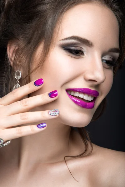 Beautiful girl with a bright evening make-up and purple manicure with rhinestones. Nail design. Beauty face.