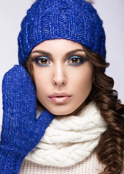 Beautiful girl with gentle makeup, curls and smile in blue knit hat. Warm winter image. Beauty face.