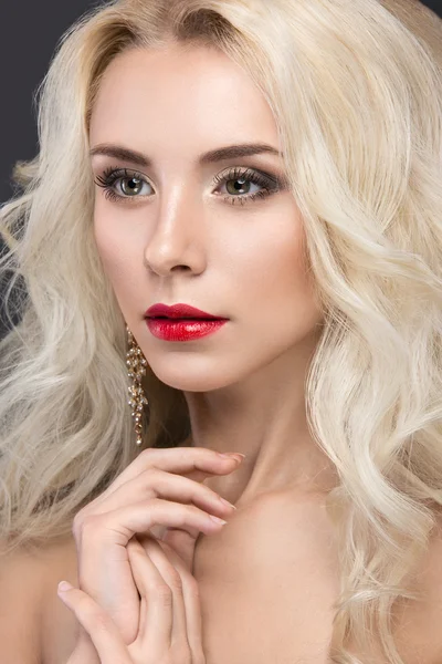 Beautiful blond woman with evening make-up, red lips and curls. Beauty face.