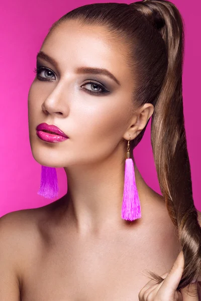 Beautiful woman with evening make-up, bright accessories and long straight hair . Smoky eyes. Fashion photo.