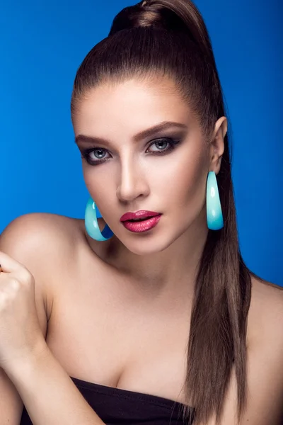 Beautiful woman with evening make-up, bright accessories and long straight hair . Smoky eyes. Fashion photo.