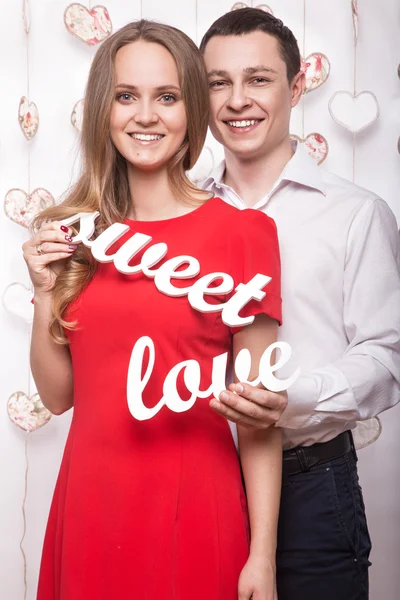 Beautiful young couple with the words Sweet love in hands. Valentine\'s Day.