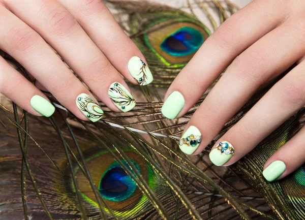 Art design manicure  with peacock feather on female hands. Close-up. Fashion nails.