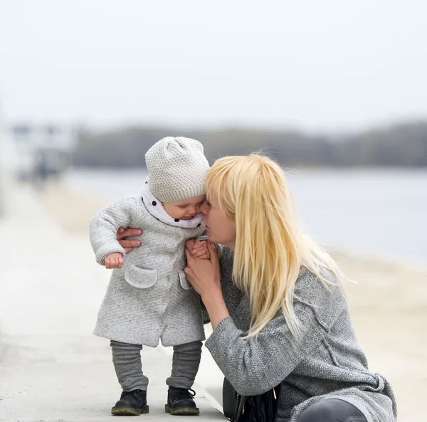 Mother gently embraces and kisses the little daughter.