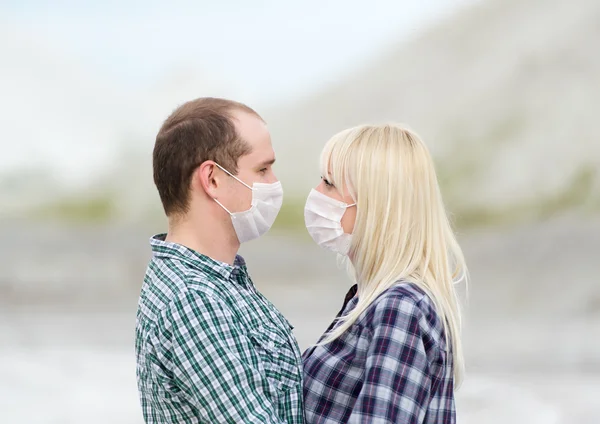 The man and the woman in respirators embrace.